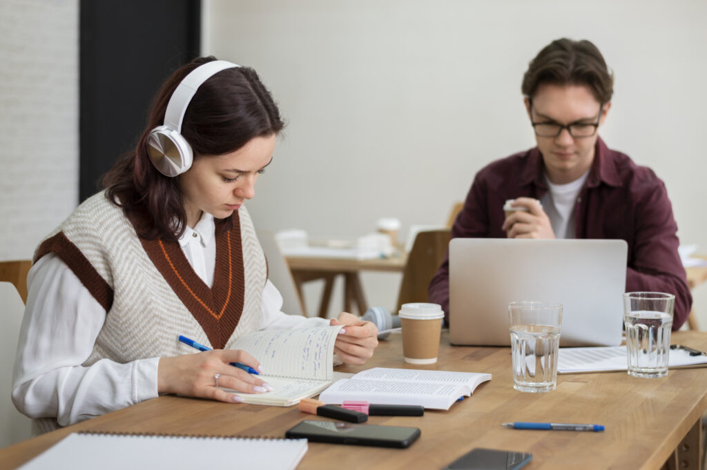 girl with headphones using laptop along her classmates group study scaled